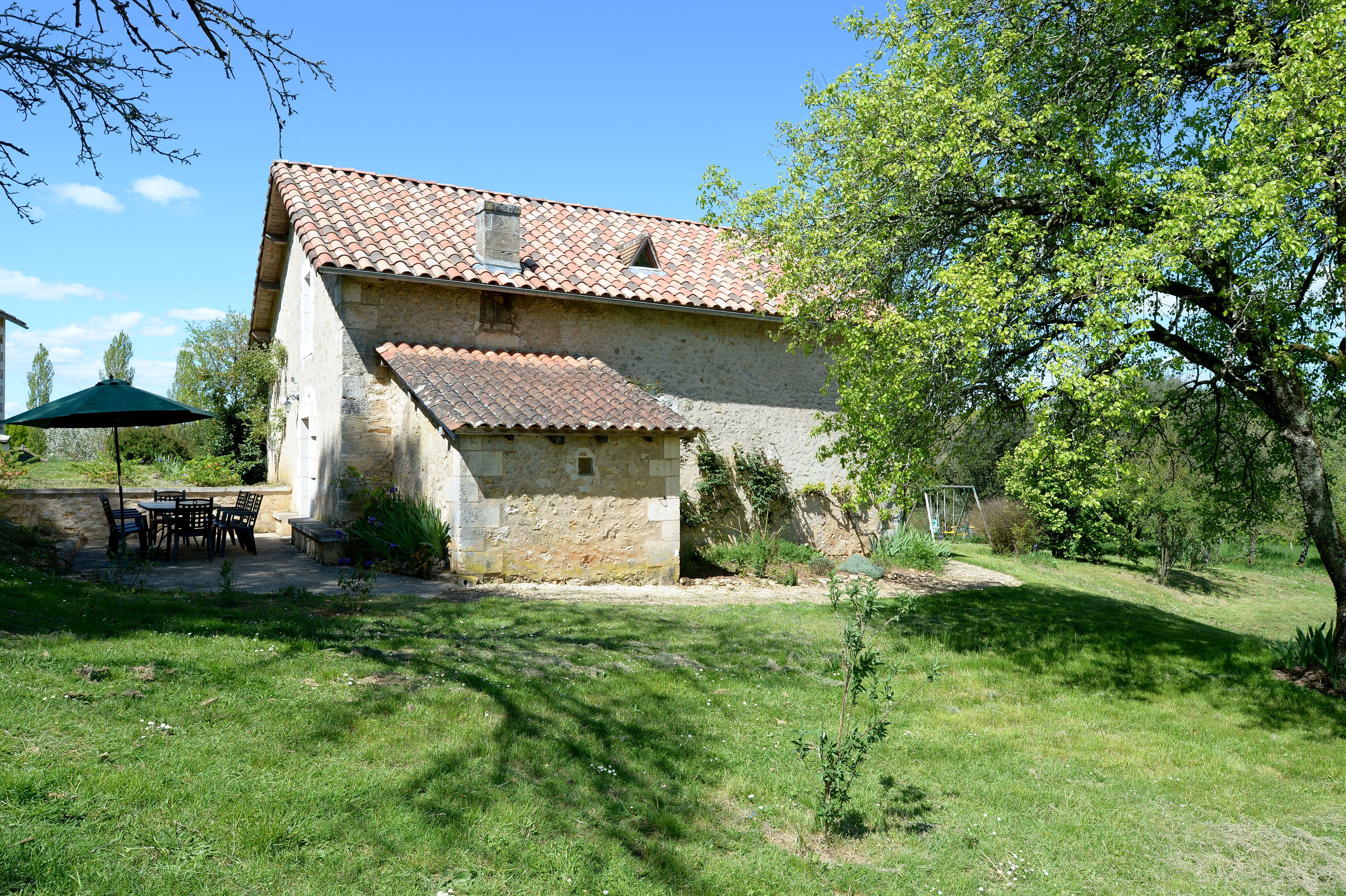 La maison avec la terrasse ombragée et espace vert, idéale pour la détente en plein air, entrée de la maison accessible aux personnes à mobilité réduite.